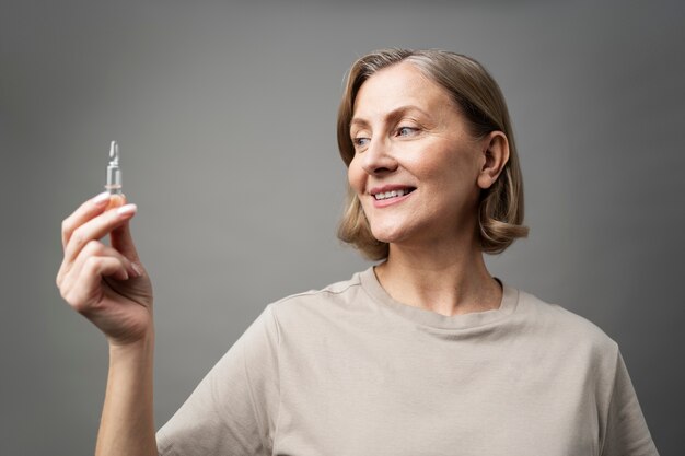Mulher sorridente de tiro médio segurando o frasco