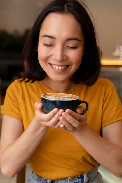 Mulher sorridente de tiro médio segurando uma xícara de café