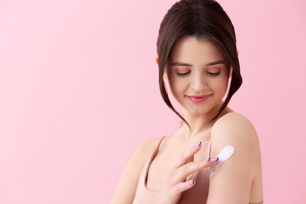Mulher sorridente de tom médio usando creme corporal
