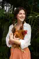 Foto grátis mulher sorridente de vista frontal segurando a galinha
