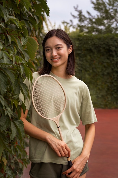 Foto grátis mulher sorridente de vista frontal segurando a raquete