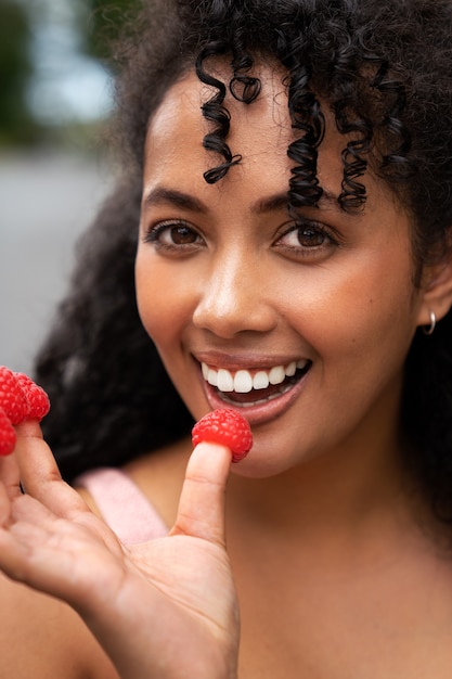 Foto grátis mulher sorridente de vista frontal segurando framboesas