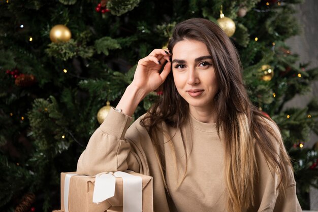 Mulher sorridente deitada no tapete fofo com presentes de Natal.