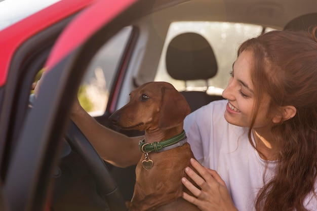 Mulher sorridente dirigindo com cachorro de perto