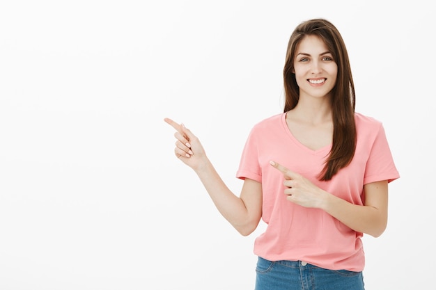 Mulher sorridente e alegre apontando para o canto esquerdo superior