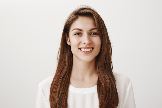 Mulher sorridente e amigável parecendo satisfeita na frente