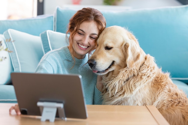 Mulher sorridente e cachorro com tablet tiro médio