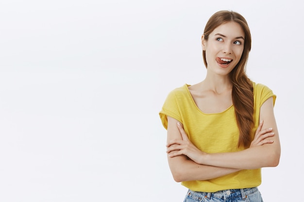 Mulher sorridente e despreocupada com os braços cruzados e parecendo intrigada à esquerda