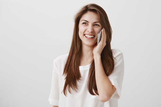 Mulher sorridente e feliz falando ao telefone, ligando para alguém