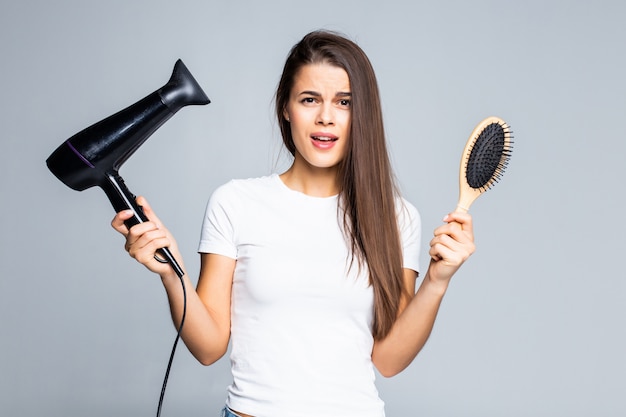 Mão feminina segurando secador de cabelo, isolado no branco