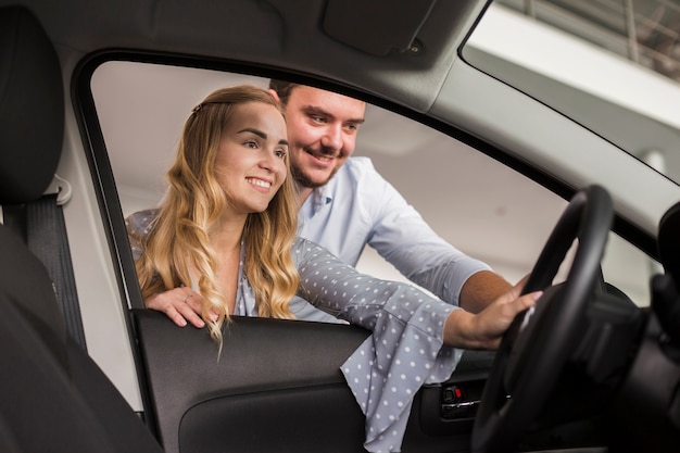 Mulher sorridente e homem olhando para um carro