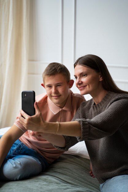 Mulher sorridente e menino tomando selfie tiro médio