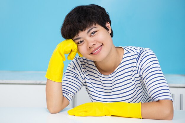 Mulher sorridente em luvas de proteção na cozinha