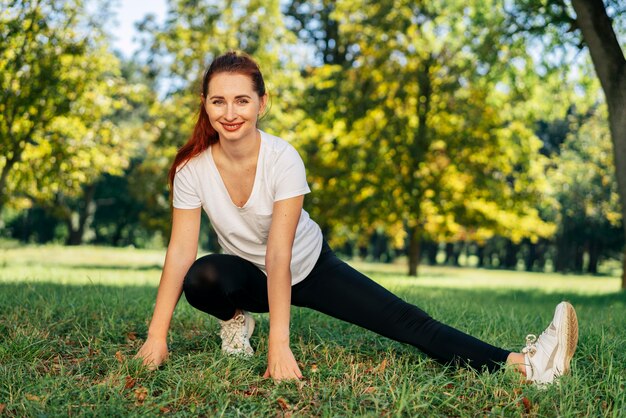 Mulher sorridente em pleno tiro fazendo exercícios