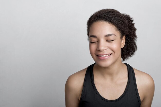 Mulher sorridente em roupas esportivas com os olhos fechados