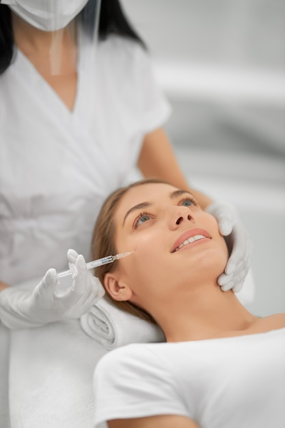 Mulher sorridente fazendo procedimento para esticar a pele