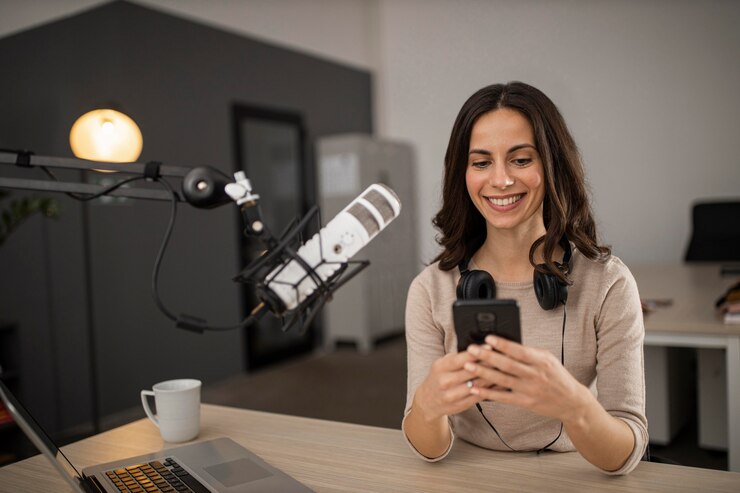 Foto grátis mulher sorridente fazendo um podcast no rádio com um microfone e um smartphone