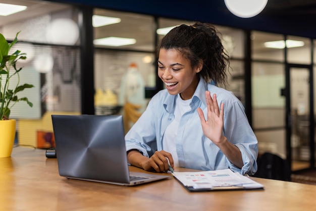 Mulher sorridente fazendo uma videochamada no escritório