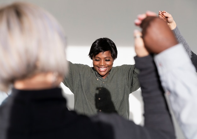 Mulher sorridente, levantando as mãos com as amigas