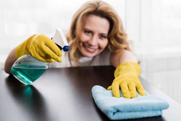 Mulher sorridente, limpando a mesa