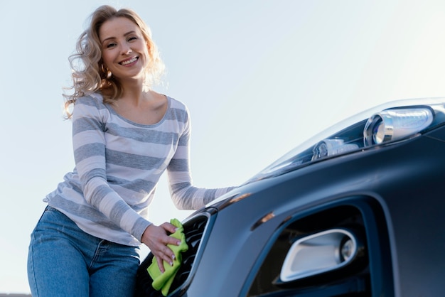 Mulher sorridente limpando o carro lá fora