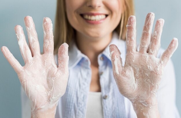 Mulher sorridente, mostrando as mãos com sabão e espuma