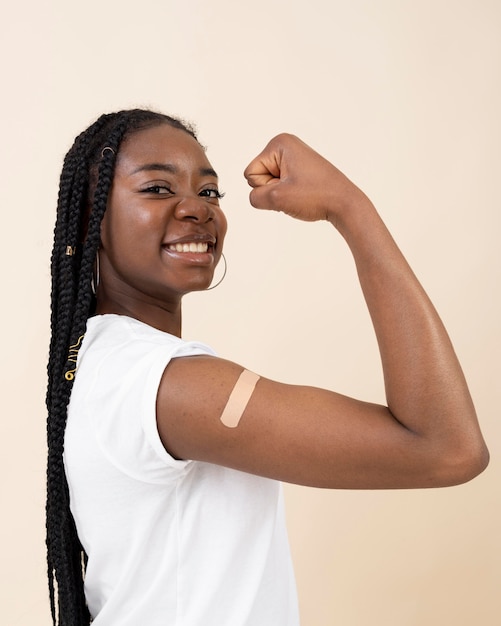 Foto grátis mulher sorridente mostrando bíceps com adesivo após tomar vacina