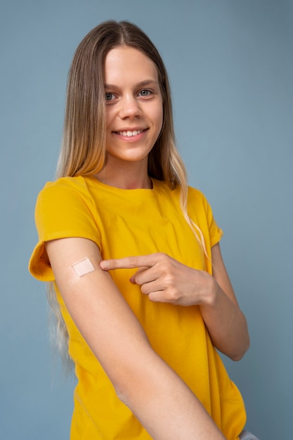 Mulher sorridente mostrando o braço com adesivo após tomar vacina