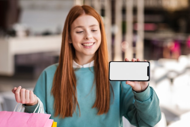 Mulher sorridente, mostrando um telefone simulado