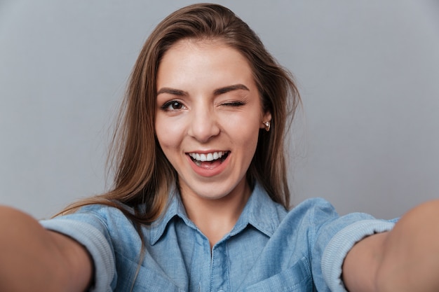 Foto grátis mulher sorridente na camisa fazendo selfie no estúdio e piscadelas