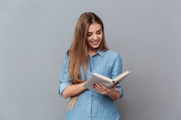 Mulher sorridente na camisa lendo livro