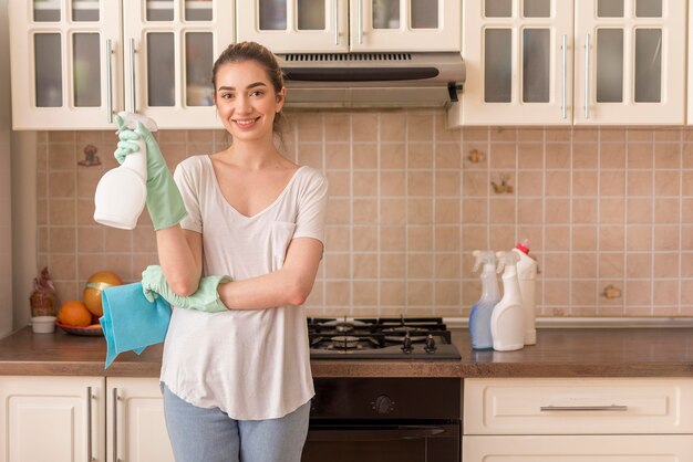 Mulher sorridente na cozinha segurando ablução e pano