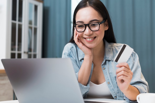 Mulher sorridente na mesa com cartão de crédito e laptop