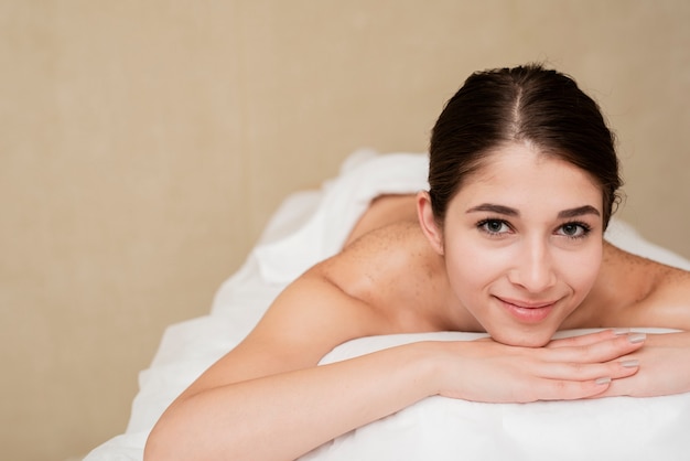 Mulher sorridente na mesa de massagem no spa a sorrir