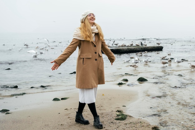 Foto grátis mulher sorridente na praia no inverno