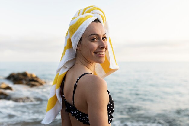 Mulher sorridente no plano médio à beira-mar