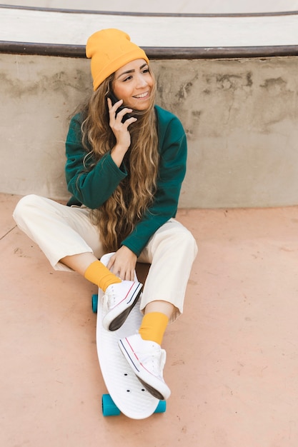 Foto grátis mulher sorridente no skate falando por telefone