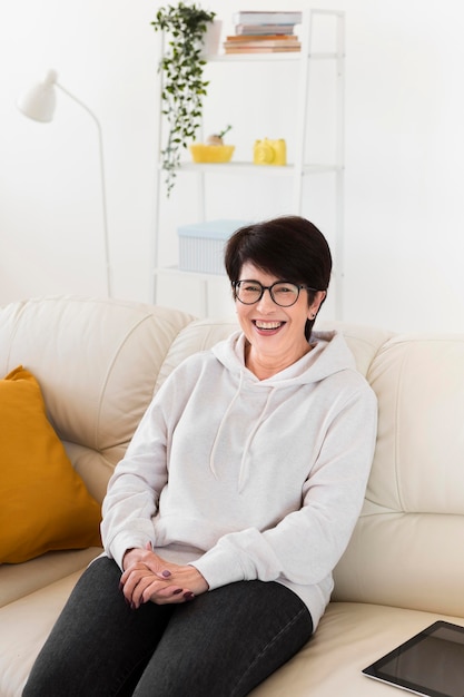 Mulher sorridente no sofá em casa com tablet