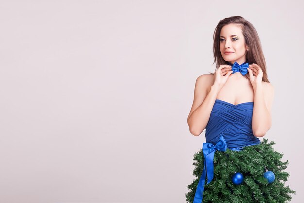 Mulher sorridente no vestido de natal conceitual em fundo cinza em foto de estúdio. natal e beleza