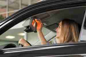 Foto grátis mulher sorridente, olhando em um espelho de carro