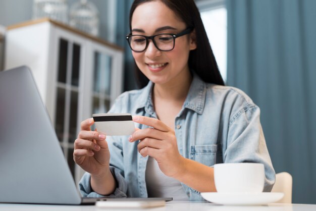 Mulher sorridente, olhando para o cartão de crédito enquanto estava na mesa