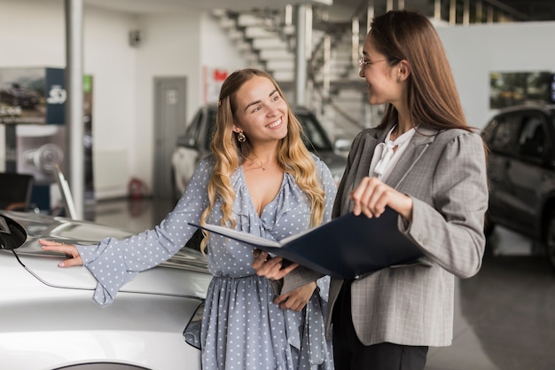 Mulher sorridente, olhando para o negociante de carro feminino