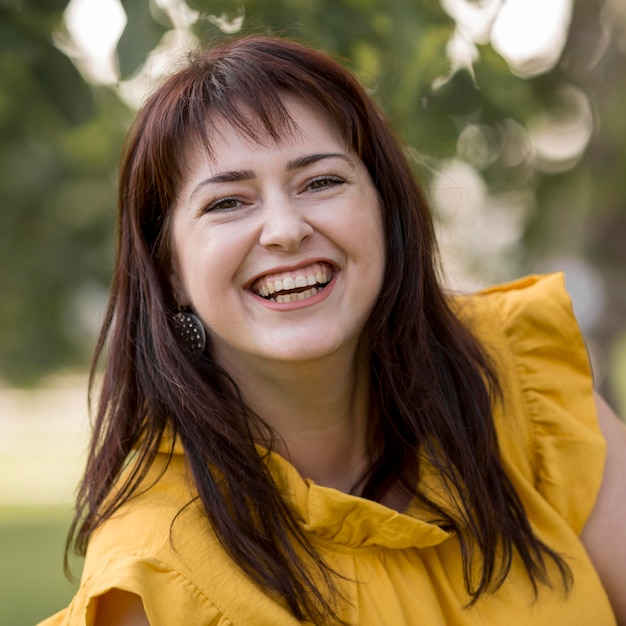 Mulher sorridente posando com um vestido amarelo do lado de fora