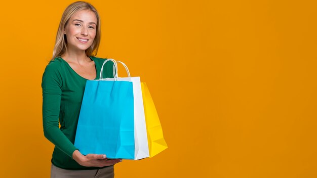 Mulher sorridente posando segurando várias sacolas de compras com espaço de cópia