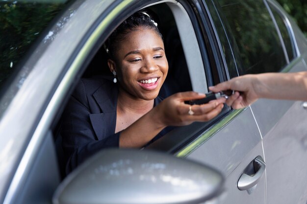 Mulher sorridente recebendo as chaves de seu carro novo