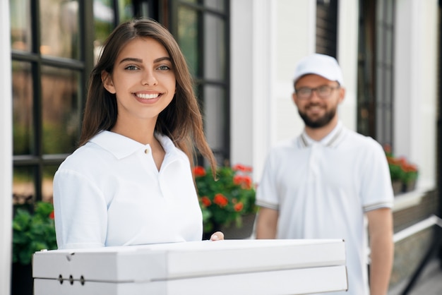 Foto grátis mulher sorridente segurando caixas de pizza