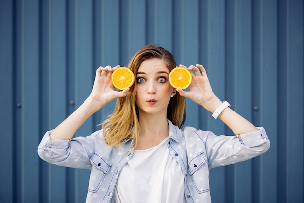 Mulher sorridente segurando duas laranja nas mãos