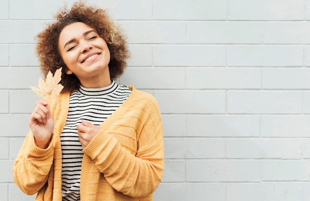 Foto grátis mulher sorridente segurando folhas outonais do lado de fora