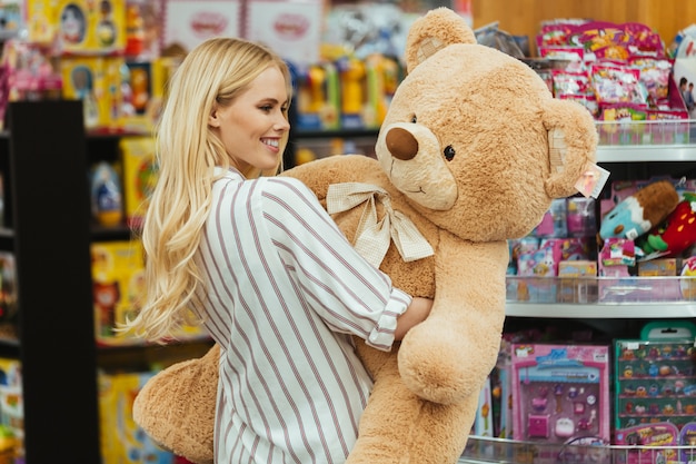 Mulher sorridente segurando o grande urso de pelúcia