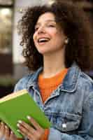 Foto grátis mulher sorridente segurando o livro de lado